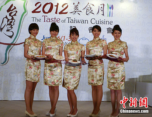 图为5月31日举行的记者会上，礼仪小姐向在场国际友人展示五样台湾特色小吃，包括蚵仔煎、肉圆、刈包、猪血糕以及生煎包等。中新社发 杜燕 摄